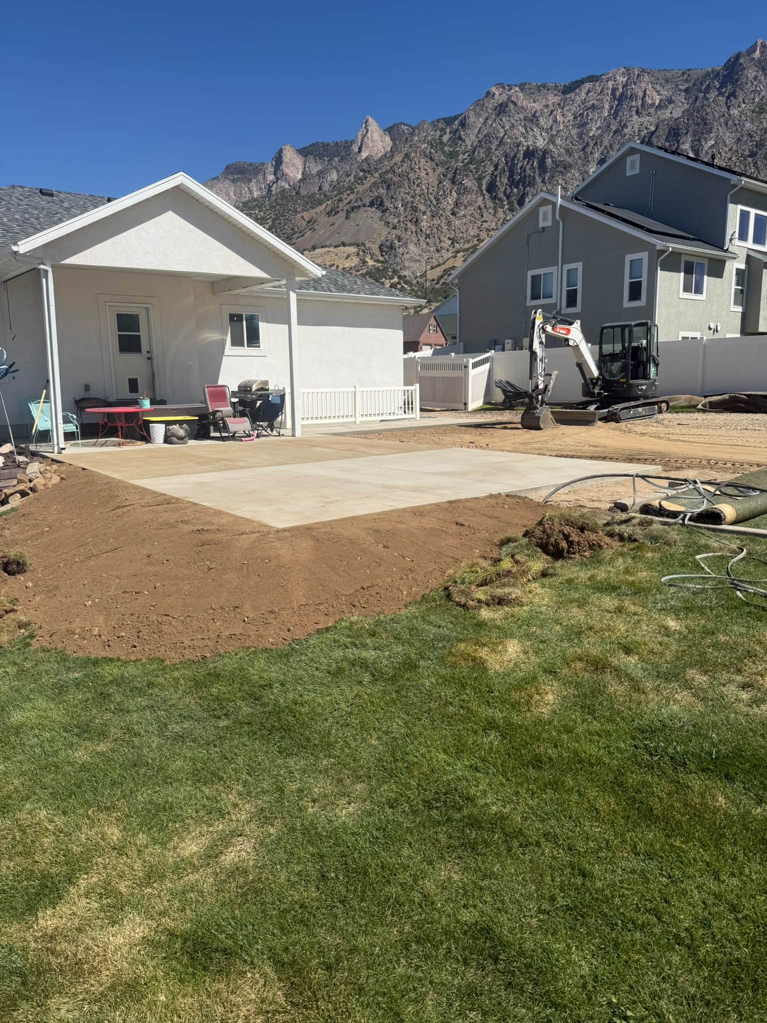 RGJ mini excavator grading a backyard pad in Ogden, Utah with Ben Lomond Peak behind